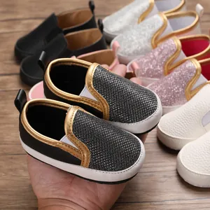 Primo piano di scarpe primi passi per neonati con suola morbida in vari colori e bordi dorati