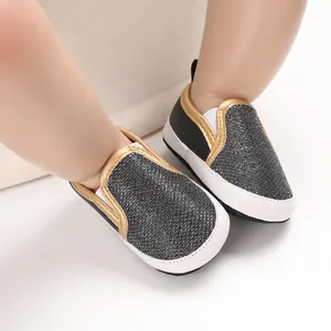 Dettaglio di scarpe da passeggio per neonati con trama nera lucida e profili dorati