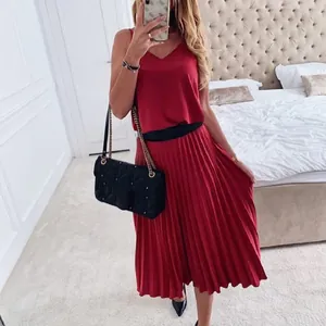 Red V-neck pleated midi dress featuring a black waistband and elegant flowy skirt