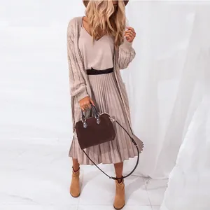 Detailed view of an elegant V-neck pleated midi dress styled with a cardigan and a handbag