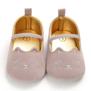 Detail shot of pink baby walking shoes with cute embroidered cat face and gold lining.