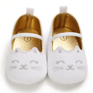Close-up of white baby walking shoes with cute silver cat embroidery and gold lining