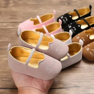 Close-up of grey baby walker shoes with cartoon cat embroidery and soft gold lining.