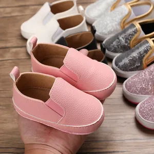 Primo piano di scarpe primi passi rosa per neonati con suola morbida e vari colori.