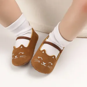 Detailed view of brown suede baby shoes with a white embroidered cartoon cat face design.