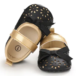 Detailansicht eleganter schwarzer Baby-Prinzessinenschuhe mit goldenen Riemen und Blumenmustern