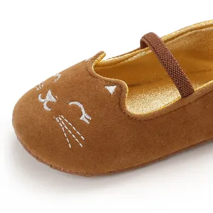 Detailed macro view of brown baby walking shoes featuring white cat face embroidery details