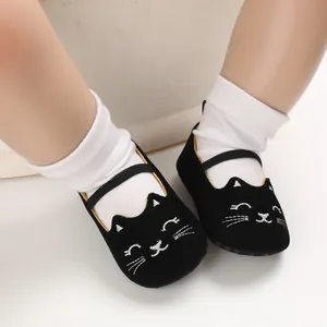 Close-up of black baby walking shoes featuring a cute cartoon cat design and soft sole.