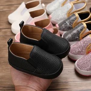 Primo piano di scarpe primi passi per neonati in pelle nera e glitter con suola morbida