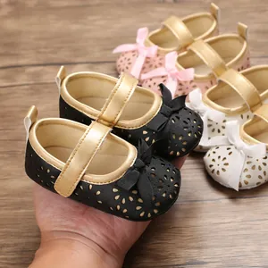 Nahaufnahme weicher Baby-Prinzessinnenschuhe mit Schleife und floralem Lochmuster.