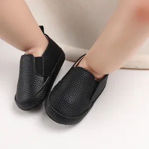 Dettaglio di scarpe primi passi nere testurizzate per neonati con suola morbida antiscivolo.