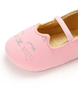 Close-up of pink baby walking shoe featuring cute embroidered cat face and gold lining