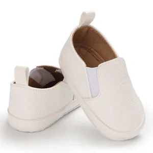Primo piano di scarpine bianche per neonato con texture morbida e fasce elastiche.