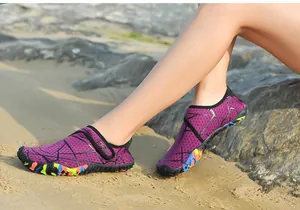 Detailansicht lila schnelltrocknender Wasserschuhe mit bunter Sohle am sonnigen Sandstrand