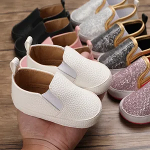 Primo piano di scarpine primi passi per neonati in pelle bianca con elastici