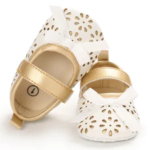 Detailansicht von weißen Baby-Prinzessin-Schuhen mit Laserschnitt-Blumen und Schleifen