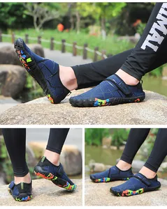 Nahaufnahme blauer atmungsaktiver Trekkingschuhe mit bunter Tarnsohle auf Felsen