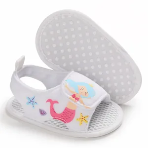 Detalle de sandalias blancas para bebé con estampado de sirena y suela antideslizante