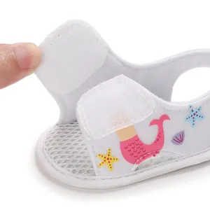 Detalle de sandalia blanca para bebé con estampado de sirena y cierre de velcro.