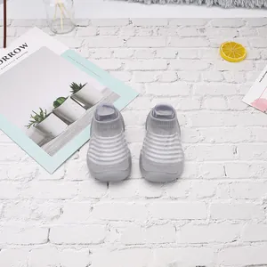 Vista superior de zapatos de punto para bebé a rayas grises y blancas sobre ladrillo