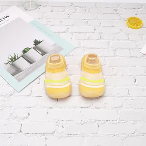 Vista superior de zapatos tipo calcetín para bebé de malla amarilla a rayas sobre ladrillo