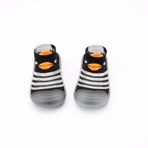 Dettaglio di scarpe a calzino per neonati in maglia traspirante con simpatico pinguino.