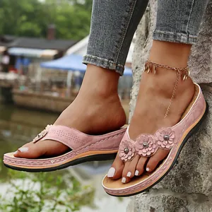 Detalle de las chanclas con cuña rosa con elegantes decoraciones florales retro