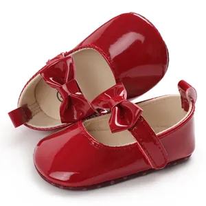 Nahaufnahme von glänzenden roten Baby-Mary-Jane-Schuhen aus Lackleder mit Schleifen