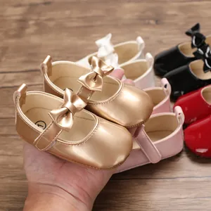 Nahaufnahme der glänzenden goldenen Baby-Lauflernschuhe aus PU-Leder mit Schleife