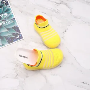 Breathable yellow knit baby sock shoes for toddlers on marble background