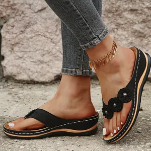 Detalle de sandalias de cuña negras con flores decorativas y patrones calados con láser
