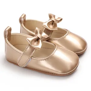 Detailansicht glänzende goldene Baby Mary Janes mit Schleife und weicher Sohle