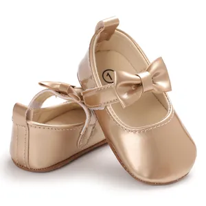 Nahaufnahme goldener Baby-Lauflernschuhe mit weicher Sohle und dekorativer Schleife für Mädchen