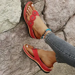 Primer plano de chanclas de cuña rojas retro con detalles florales cortados con láser.
