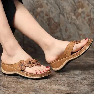 Detalle con adornos florales vintage y patrones cortados a láser en sandalias de cuña.