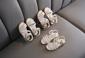 Detailansicht von Mädchen-Sandalen mit Perlen in verschiedenen Farben auf einem Sofa