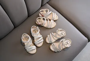 Elegante Mädchen-Sandalen mit Perlen in Rosa und Weiß auf grauem Sitz präsentiert