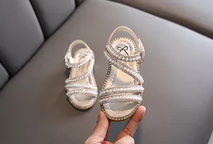Detailansicht eleganter weißer Mädchensandalen mit Perlen und vielen Strasssteinen