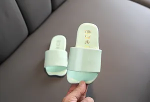 Primer plano detallado de pantuflas infantiles verde menta con marca coreana en suela