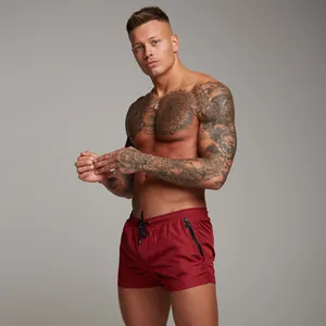 Detailed view of men's burgundy gym shorts with zipper pocket shown on a fit model