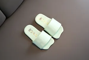 Detalle de chanclas infantiles verde claro de estilo coreano con logo dorado.