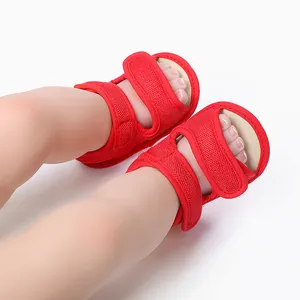 Gedetailleerde close-up van rode mesh babysandalen aan babyvoetjes voor de zomer