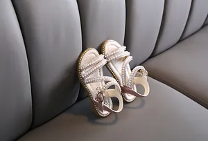 Detailansicht von rosa Mädchensandalen mit dekorativen Perlen und Strassriemen