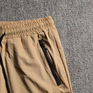 Close-up detail of men's khaki running shorts featuring a secure black zipper pocket