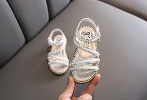 Nahaufnahme von weißen Sandalen für Mädchen mit eleganten Perlen und Strasssteinen