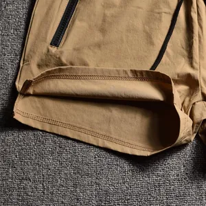 Close-up of khaki men's sports shorts showing zipper pocket and durable stitching details
