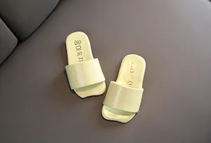Vista detallada de chanclas amarillas para niños de estilo coreano en fondo de cuero