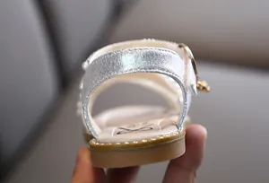 Makroansicht des silbernen Metallic-Riemens und Perlendetails der Mädchensandale