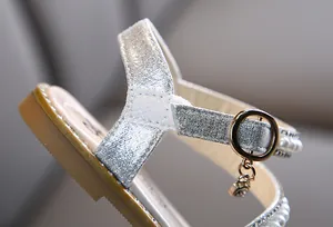 Detailansicht der silbernen Glitzertextur und Perlenakzente an einer Mädchensandale