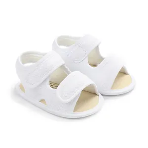 Close-up of white breathable mesh baby sandals with velcro straps for infant walkers.